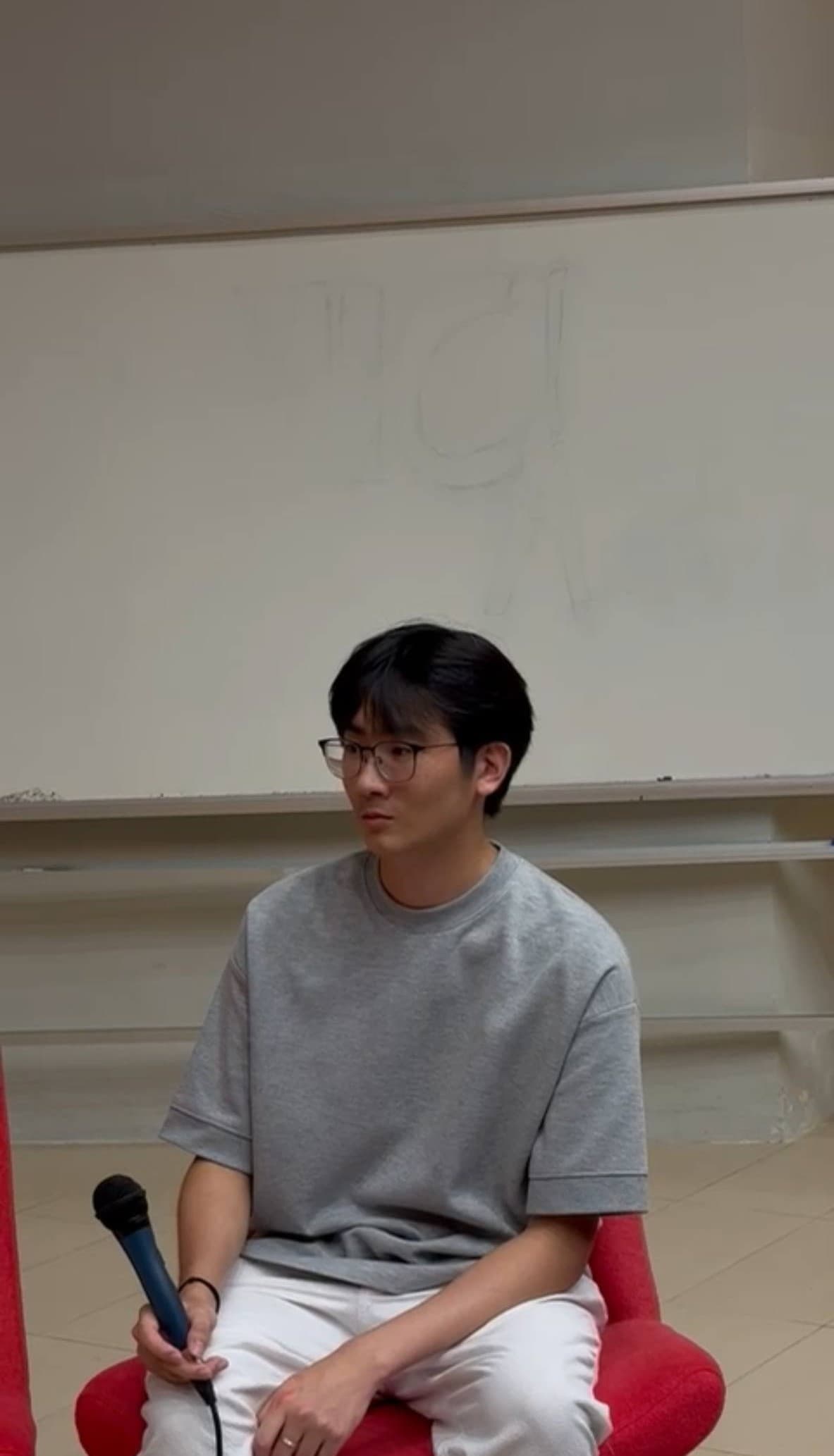 Jovan seated with a microphone in front of a whiteboard